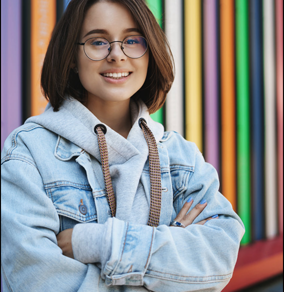 Estudante sorrindo com livros ao fundo.